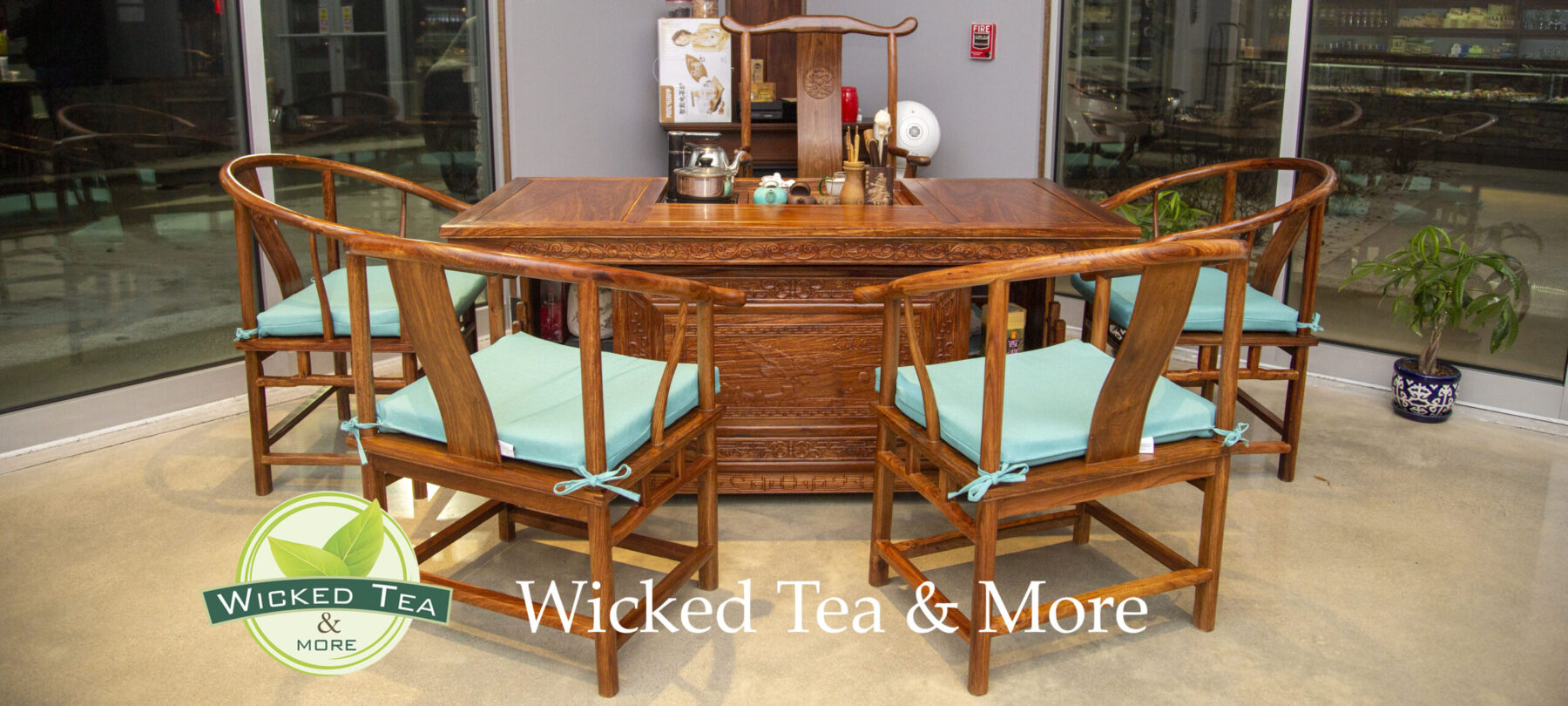 A wooden table with 4 chairs. A tea set is laid out.